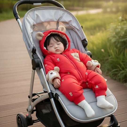 Bebe portant la combinaison rouge Kalinatur motif ours dans une poussette, tenue chaude pour l hiver