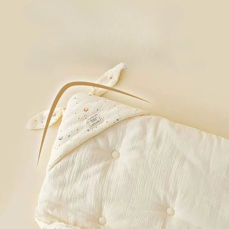 Couverture d’emmaillotage pour bébé en mousseline ivoire avec capuche à oreilles, présentée à plat dans un décor doux Kalinatur.