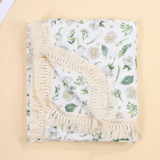 Couverture légère pour bébé Kalinatur, motif fleurs vertes sur fond blanc, avec bordure à franges bohème.
