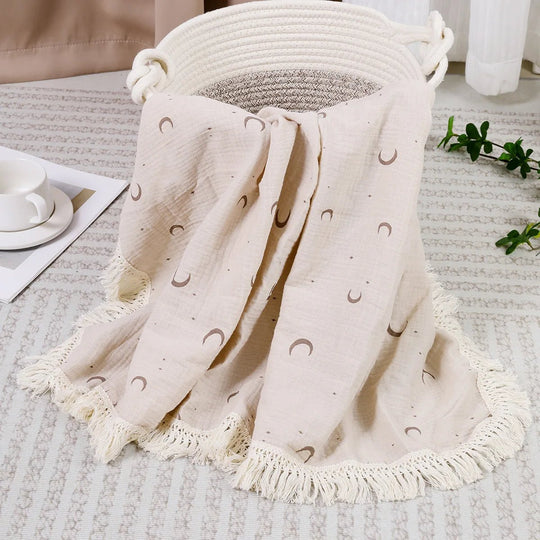 Couverture légère pour bébé Kalinatur, motif lunes beige sur tissu écru avec franges décoratives.
