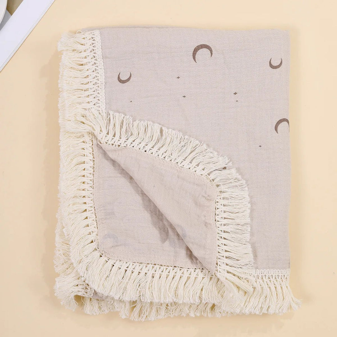 Couverture légère pour bébé Kalinatur avec motifs lune bohème et bordure à franges crème.
