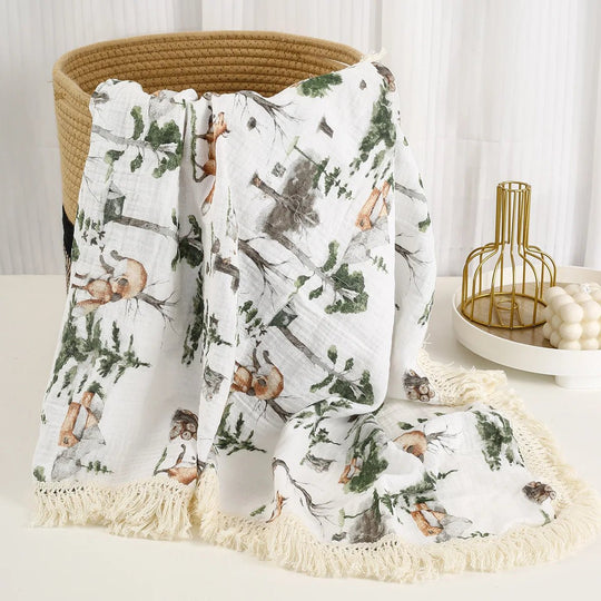 Couverture légère pour bébé Kalinatur en mousseline, motif forêt avec animaux et franges décoratives.
