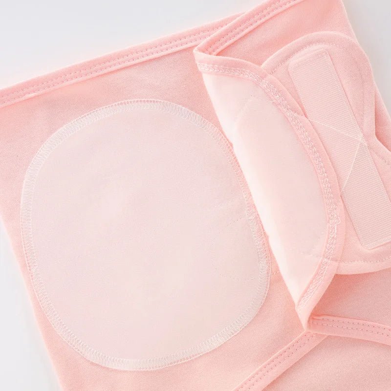 Gros plan sur la fermeture croisée du nid d’ange rose pâle pour nouveau-né, montrant les coutures et les attaches en tissu doux.