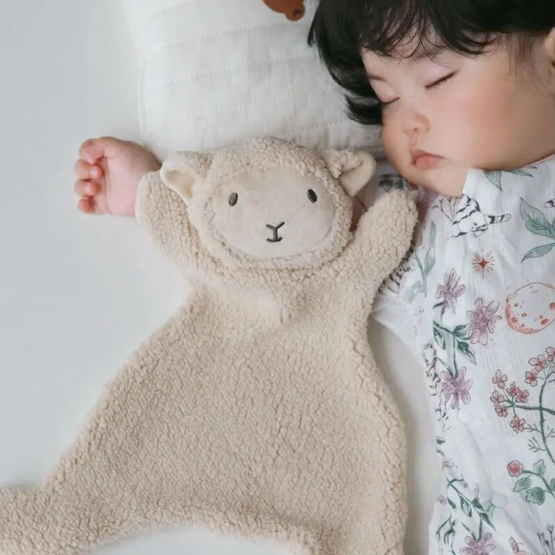Bébé endormi avec un doudou agneau beige en bouclette douce