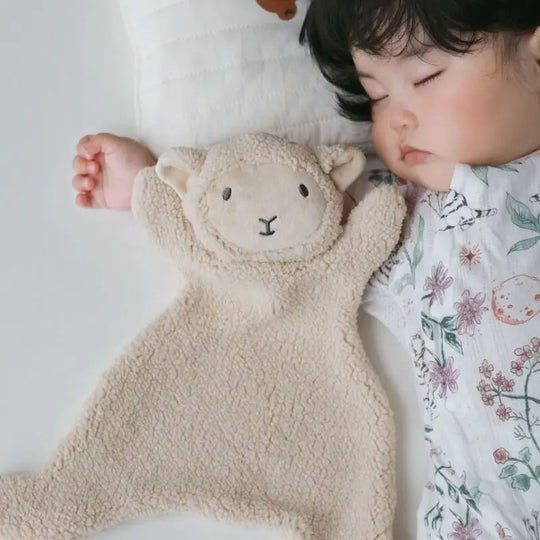 Bébé endormi avec un doudou agneau beige en bouclette douce