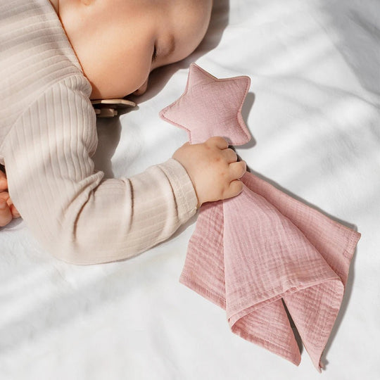 Bébé qui dort en tenant un doudou étoile rose en double gaze Kalinatur