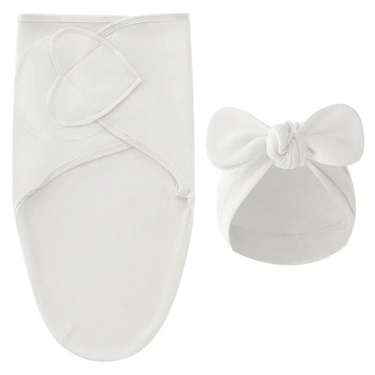 Nid d’ange blanc pour nouveau-né avec bonnet assorti à nœud, présenté sur fond clair.