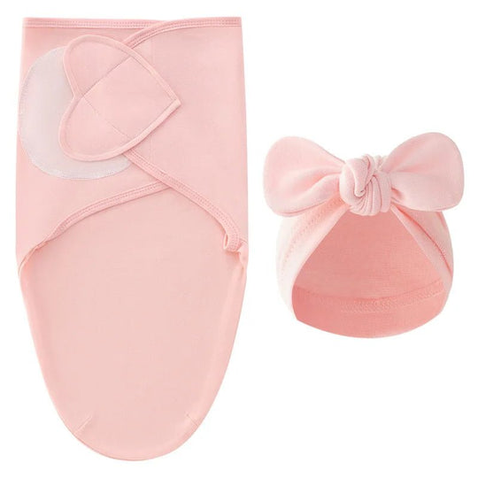 Nid d’ange rose pour nouveau-né avec bonnet assorti à nœud, présenté sur fond clair.