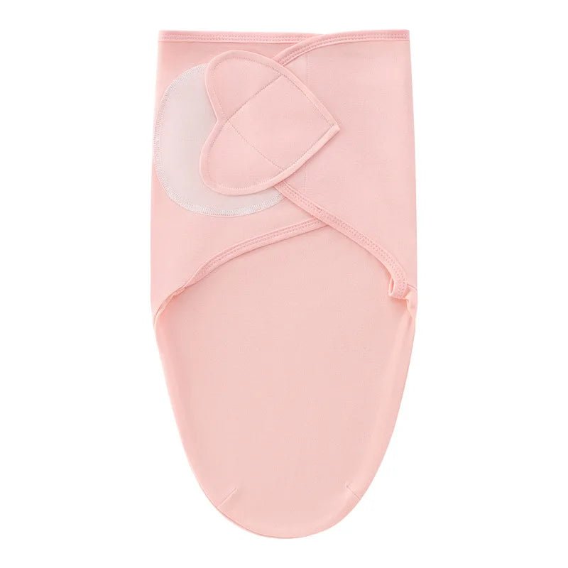 Nid d’ange rose pâle pour nouveau-né, avec fermeture croisée en tissu doux, présenté sur fond clair.