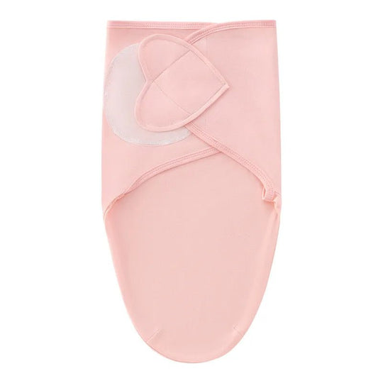 Nid d’ange rose pâle pour nouveau-né, avec fermeture croisée en tissu doux, présenté sur fond clair.