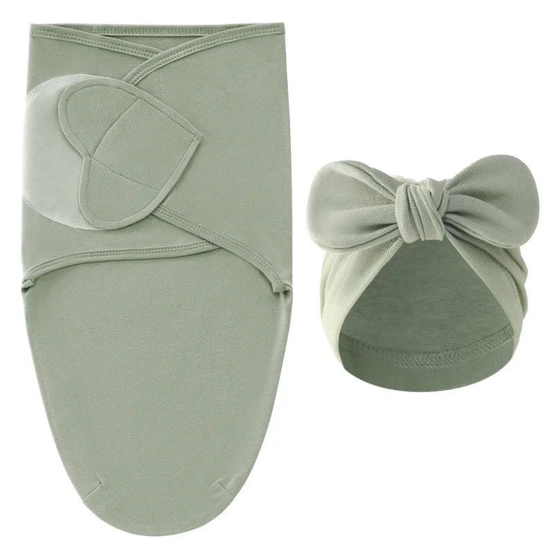 Nid d’ange vert sauge pour bébé avec bonnet assorti à nœud, présenté sur fond clair.