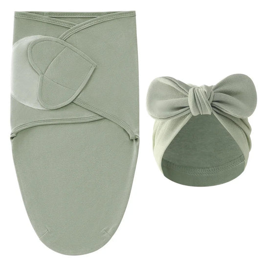 Nid d’ange vert sauge pour bébé avec bonnet assorti à nœud, présenté sur fond clair.