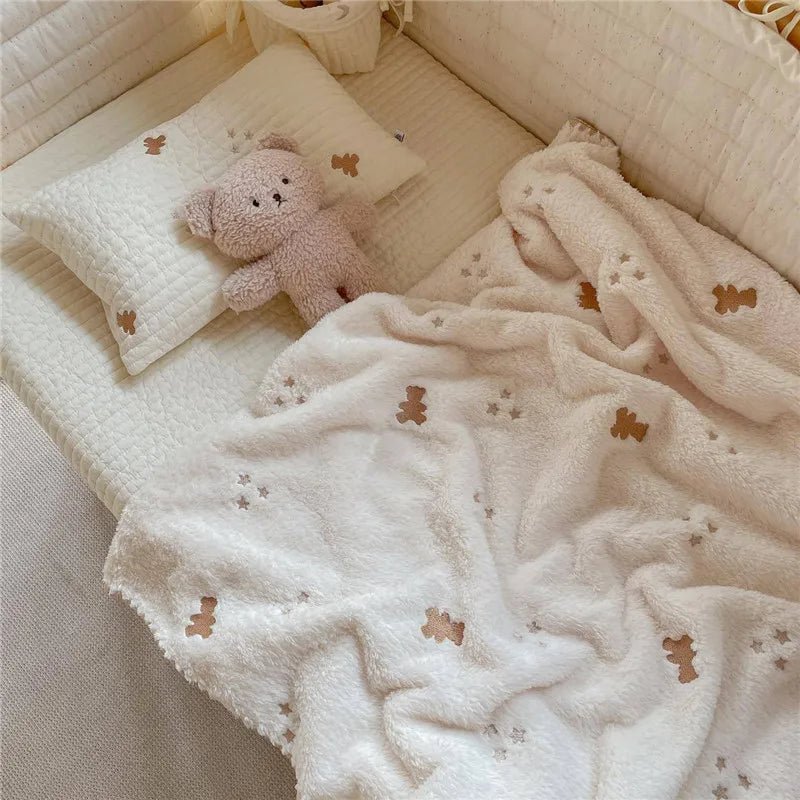 Plaid bébé crème avec motifs oursons posé sur un lit cocon avec coussin et doudou Kalinatur