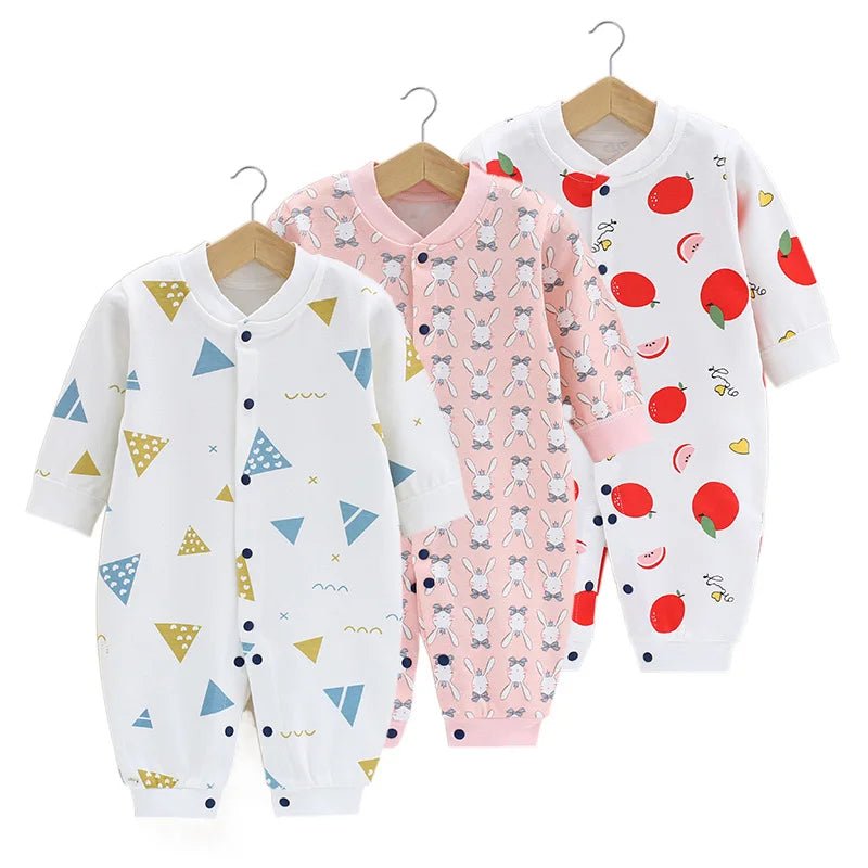 Lot de trois pyjamas bébé : un imprimé triangles graphiques jaune et bleu, un rose avec lapins blancs répétés, et un blanc décoré de grandes pommes rouges.